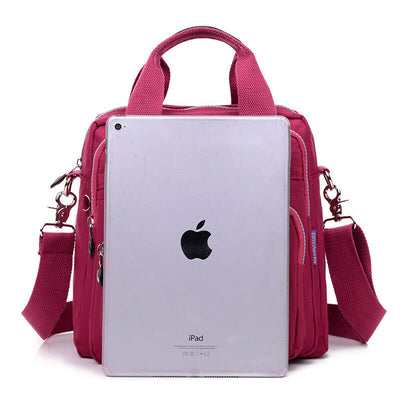 Sac à main rose avec bandoulière, compartiments multiples, et tablette iPad argentée en avant-plan. Accessoire mode femme, pratique et élégant.