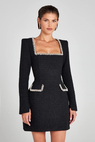 Robe noire élégante en tweed avec col carré et bordures perlées, manches longues, poches décoratives, portée par une femme. Mode chic et sophistiquée.