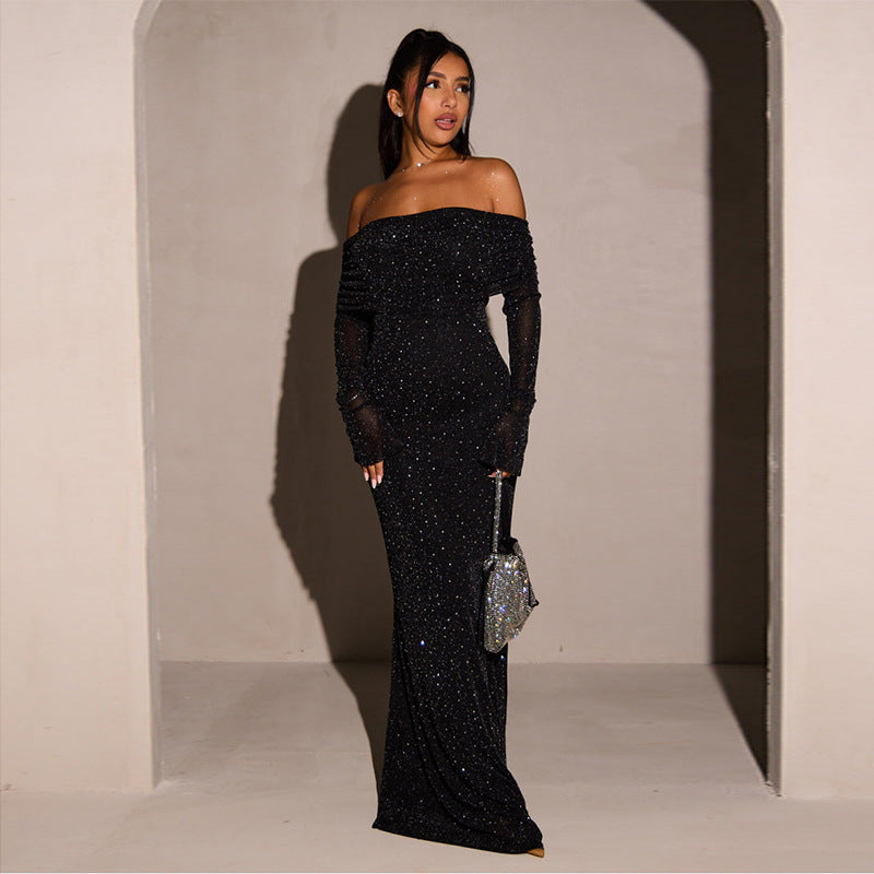 Robe longue noire à paillettes, épaules dénudées, portée par une femme élégante, tenant un sac à main argenté. Mode soirée glamour et chic.
