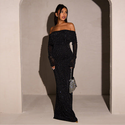 Robe longue noire à paillettes, épaules dénudées, portée par une femme élégante, tenant un sac à main argenté. Mode soirée glamour et chic.