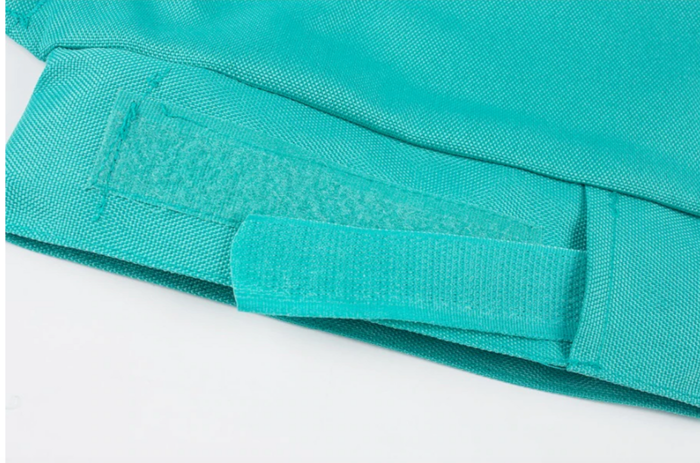 Gros plan sur une fermeture velcro turquoise sur un tissu, montrant les détails de la texture et de la couture. Accessoire textile pratique et ajustable.
