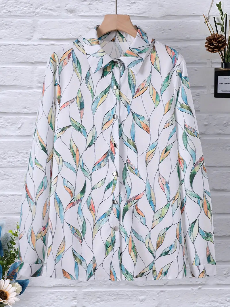 Chemise à motifs feuilles colorées sur fond blanc, suspendue sur un cintre en bois, mur en briques blanches en arrière-plan, style décontracté.