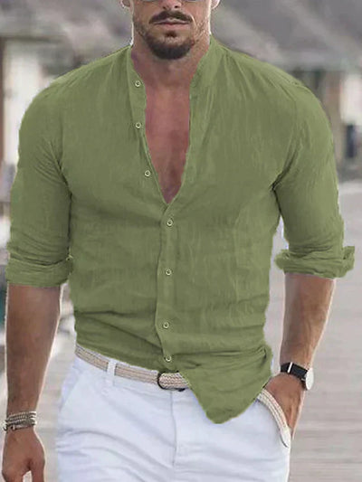 Homme portant une chemise verte en lin, manches retroussées, avec un pantalon blanc et une ceinture tressée, style décontracté estival.
