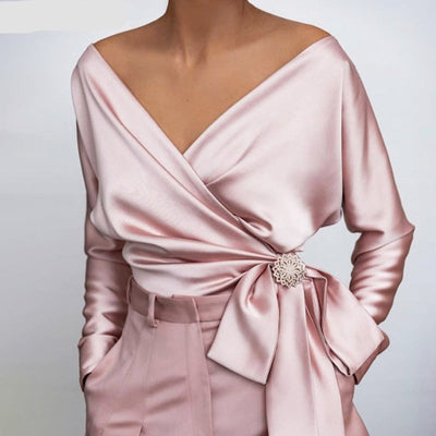 Blouse en satin rose élégante avec décolleté en V, manches longues et nœud décoratif, tenue chic pour soirée ou événement spécial.