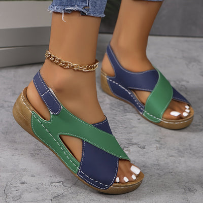 Sandales compensées bicolores bleu et vert pour femme, avec semelle en liège et chaîne dorée à la cheville, sur fond de sol gris.
