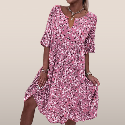 Robe d'été rose à motifs floraux, manches courtes, col en V, portée par une femme. Style décontracté, mode féminine, tendance estivale.