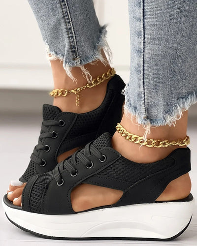 Chaussures compensées noires en maille avec semelle épaisse blanche, portées avec un jean déchiré et bracelet de cheville doré. Mode tendance femme.