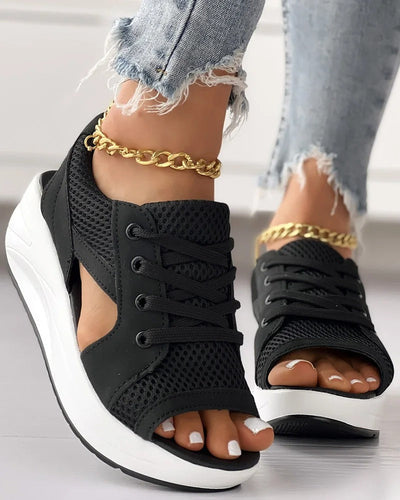 Chaussures ouvertes noires à lacets pour femme, semelle épaisse blanche, portées avec un jean déchiré et bracelet chaîne doré. Mode tendance.
