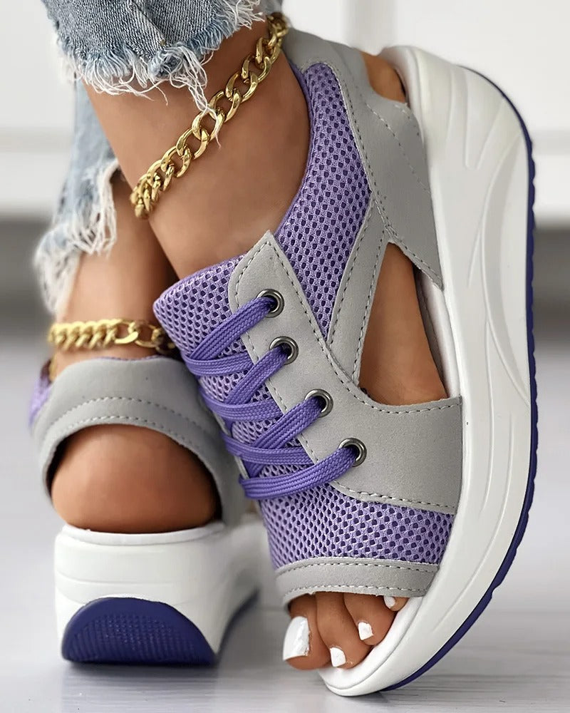 Chaussures de sport violettes et grises pour femmes avec semelles compensées, lacets et détails en maille, portées avec un jean déchiré et bracelet doré.