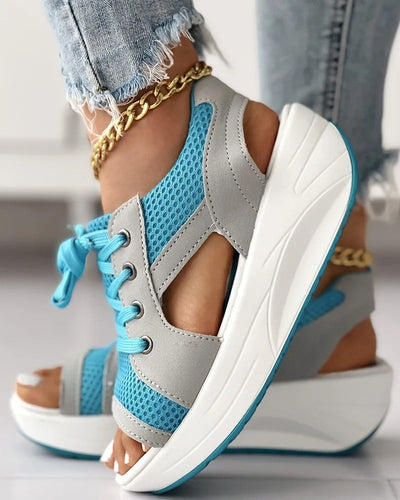 Chaussures compensées sport bleu et gris pour femme, avec lacets et semelle épaisse blanche, portées avec un jean déchiré et bracelet chaîne doré.