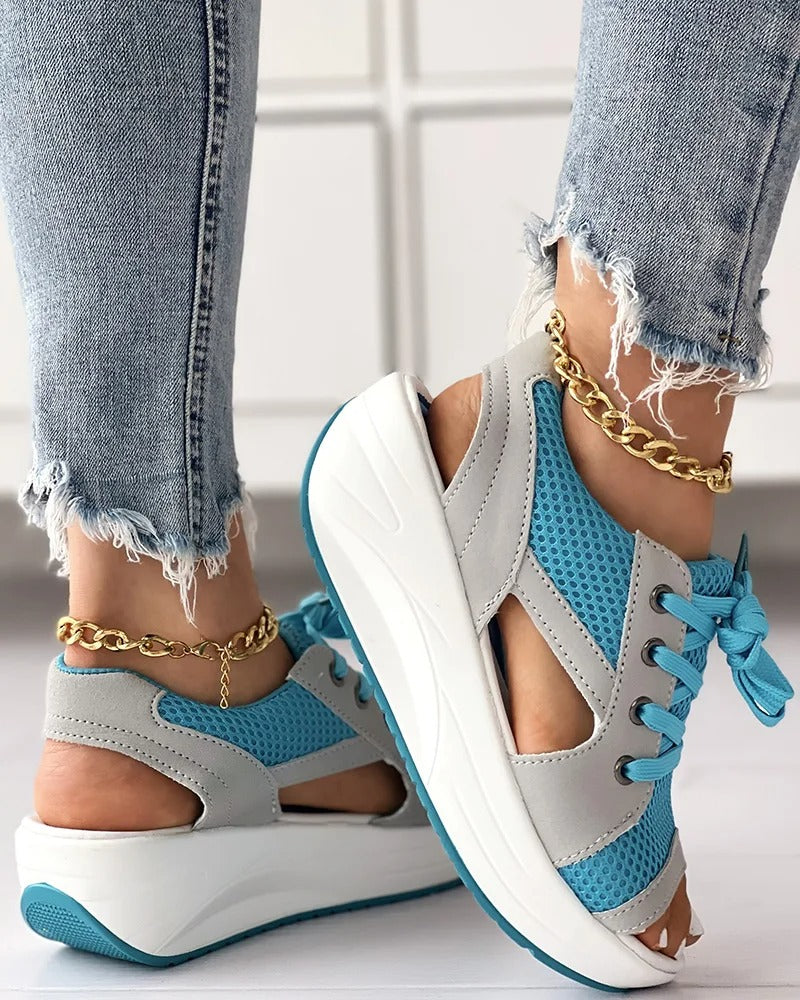 Chaussures de sport ouvertes bleu et gris avec semelles compensées, portées avec un jean déchiré et bracelets de cheville dorés. Mode féminine tendance.