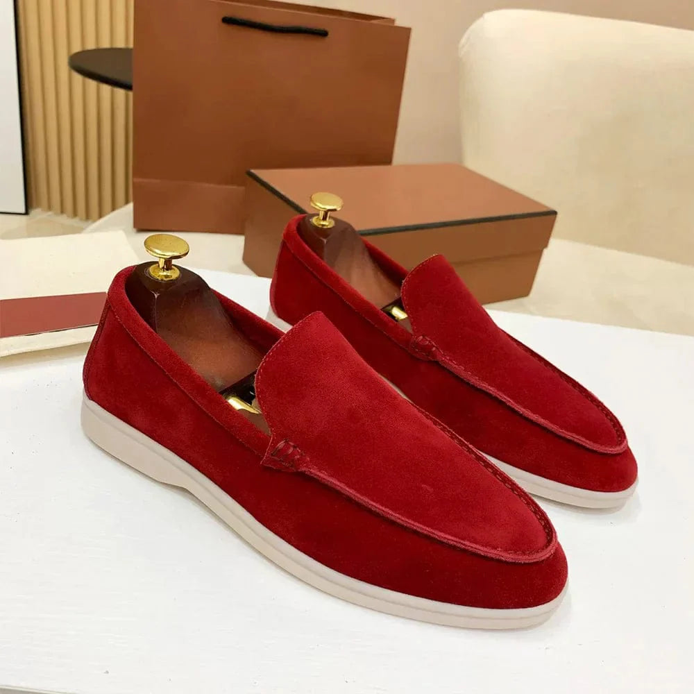 Mocassins rouges en daim pour homme sur une table blanche, avec boîte marron en arrière-plan. Chaussures élégantes, mode masculine, style décontracté.