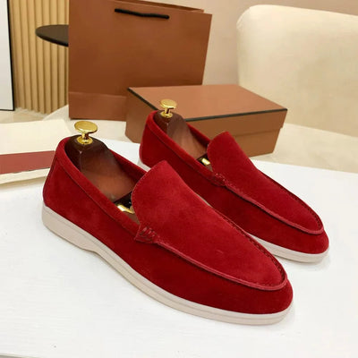 Mocassins rouges en daim pour homme sur une table blanche, avec boîte marron en arrière-plan. Chaussures élégantes, mode masculine, style décontracté.