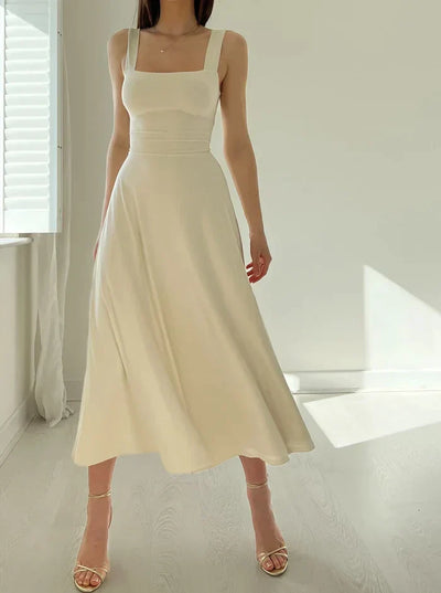 Robe longue beige élégante, sans manches, portée par une femme dans une pièce lumineuse. Mode féminine, style minimaliste, tendance été.