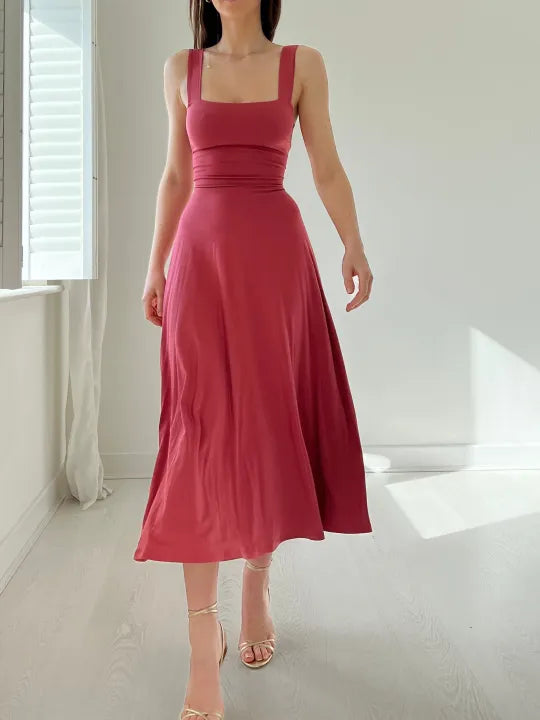 Robe longue rose sans manches, élégante et fluide, portée par une femme dans une pièce lumineuse. Mode féminine, style chic et moderne.