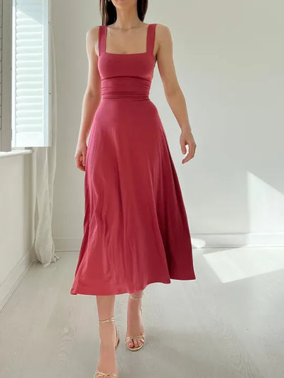Robe longue rose sans manches, élégante et fluide, portée par une femme dans une pièce lumineuse. Mode féminine, style chic et moderne.