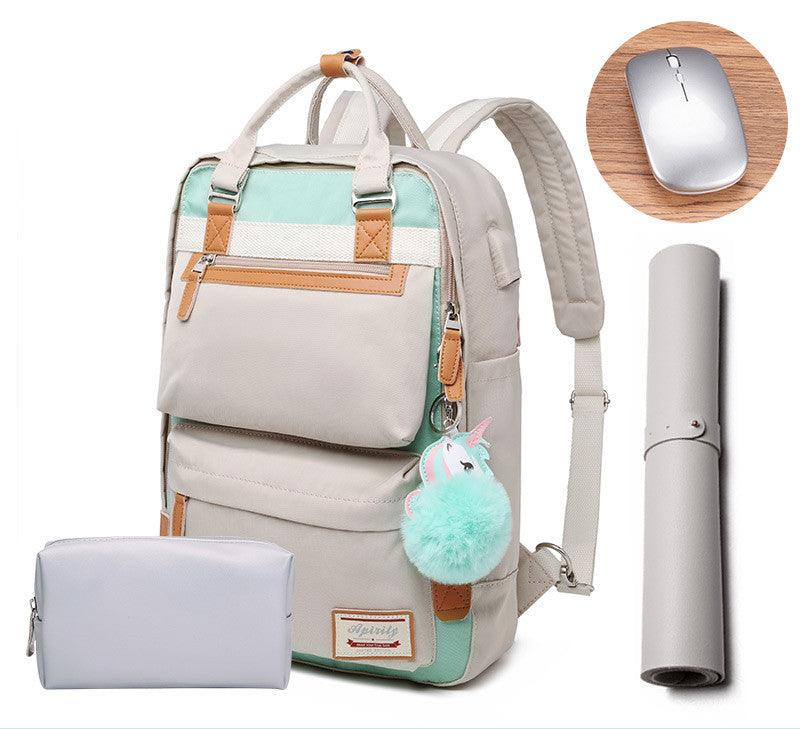 Sac à dos beige et vert menthe avec pompon licorne, accompagné d'une trousse grise, d'un tapis de souris enroulé et d'une souris sans fil argentée.