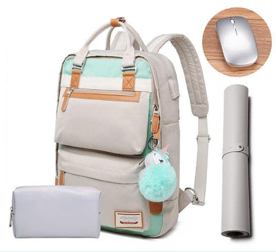 Sac à dos beige et vert menthe avec pompon licorne, accompagné d'une trousse grise, d'un tapis de souris enroulé et d'une souris sans fil argentée.