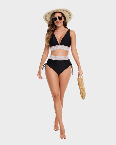Femme en maillot de bain noir avec chapeau de paille, lunettes de soleil et sac en osier, marchant sur fond blanc. Mode plage été.