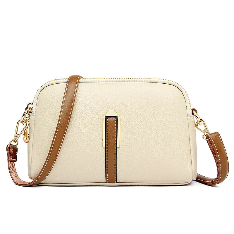Sac à main en cuir beige avec bandoulière marron, détails dorés, design élégant et moderne. Accessoire mode femme tendance.