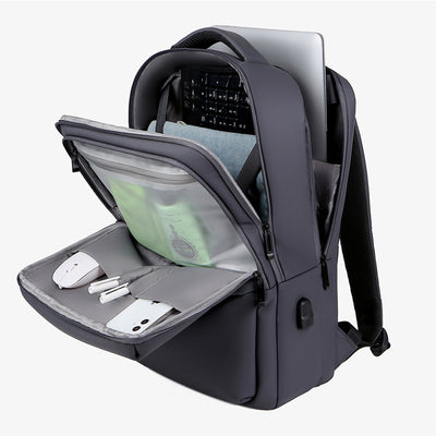Sac à dos gris moderne avec compartiment pour ordinateur portable, poches pour accessoires technologiques, design ergonomique et port USB intégré.