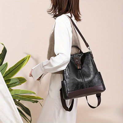 Sac à dos en cuir noir élégant porté par une femme, design moderne avec détails marron, idéal pour mode urbaine et usage quotidien.