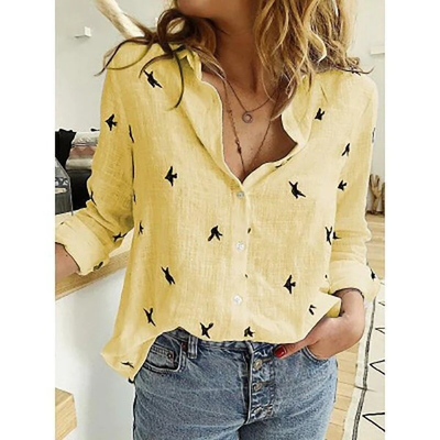 Femme portant une chemise jaune à motifs d'oiseaux noirs, manches retroussées, associée à un jean bleu décontracté. Mode tendance et décontractée.