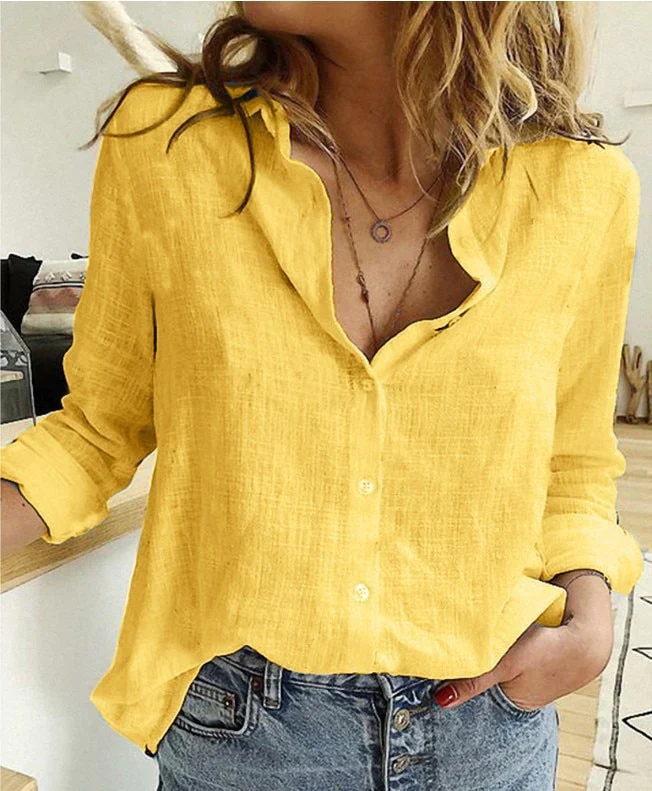 Femme portant une chemise en lin jaune vif, manches retroussées, col ouvert, associée à un jean décontracté. Mode estivale tendance.