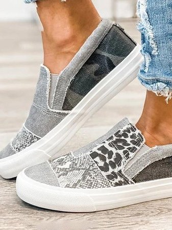 Chaussures slip-on grises à motifs léopard et camouflage, portées avec un jean déchiré. Sneakers tendance pour un look décontracté et moderne.