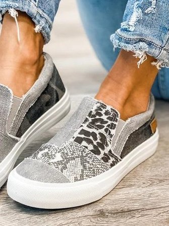 Chaussures slip-on grises à motifs léopard et serpent, portées avec un jean déchiré. Style décontracté, tendance et moderne.
