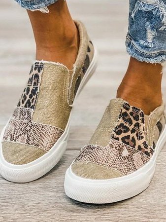 Chaussures slip-on en toile beige avec motifs léopard et serpent, semelles blanches, portées avec un jean déchiré. Mode décontractée tendance.