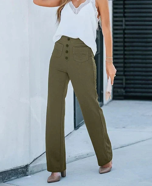 Femme portant un pantalon taille haute kaki avec boutons, top blanc en dentelle, talons beiges, tenant une pochette. Mode élégante et tendance.