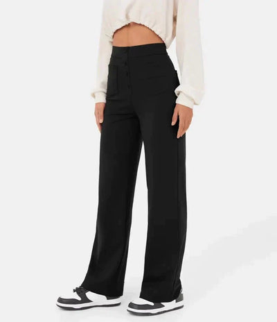 Pantalon noir taille haute femme, coupe large, porté avec un haut blanc court et des baskets noires et blanches. Mode féminine élégante et décontractée.