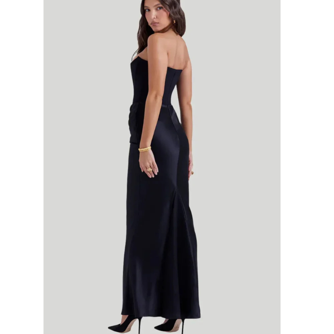 Robe de soirée noire élégante, sans bretelles, portée par une femme, avec des talons noirs et un bracelet doré. Mode féminine chic et sophistiquée.