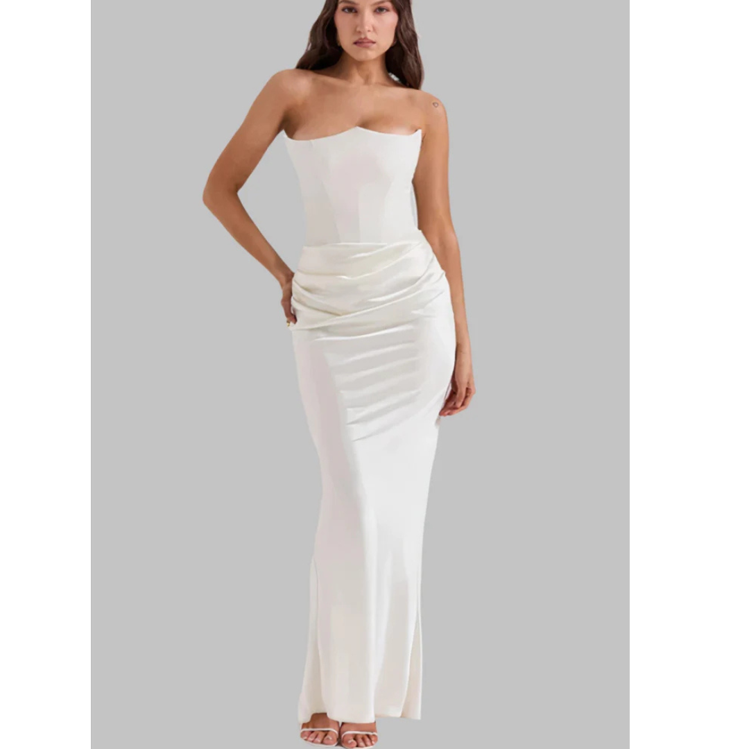 Robe longue blanche élégante sans bretelles, ajustée, avec drapé à la taille, portée par une femme sur fond gris. Mode féminine chic et sophistiquée.