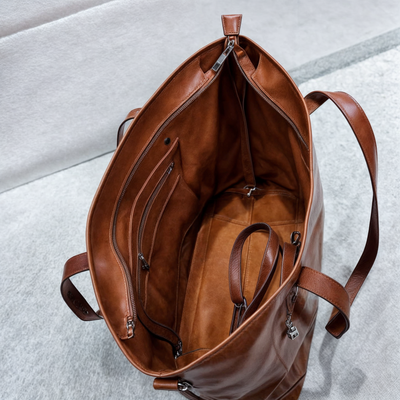 Sac cabas en cuir marron ouvert, intérieur spacieux avec poches zippées, poignées robustes, design élégant, idéal pour le shopping ou le voyage.