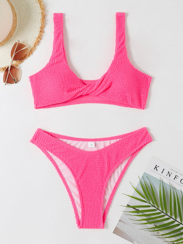 Bikini rose texturé sur fond blanc, accompagné d'un chapeau de paille, lunettes de soleil et magazine. Maillot de bain tendance pour l'été.