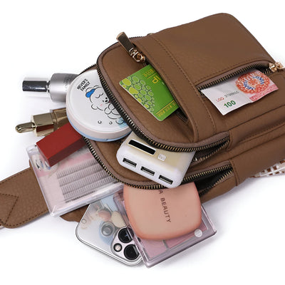 Sac à main marron ouvert avec produits de beauté, smartphone, chargeur USB, carte de crédit et billets. Accessoires de mode et technologie.