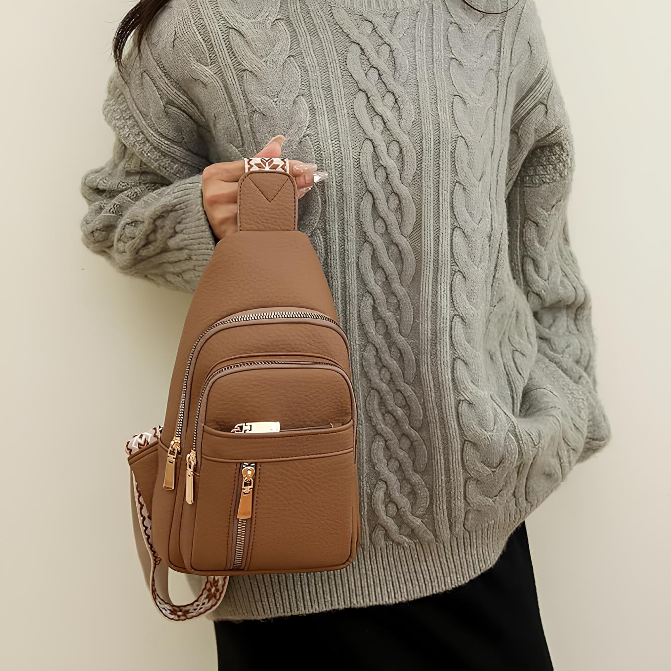 Femme portant un pull en laine torsadée gris avec un sac à dos en cuir marron à bandoulière, mode automne-hiver, accessoires tendance.