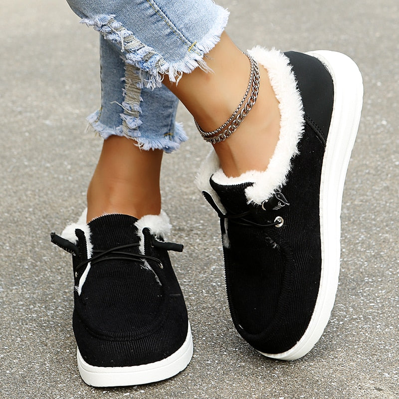 Chaussures noires en daim avec doublure en fourrure blanche, portées avec un jean déchiré et bracelet chaîne, mode décontractée femme.