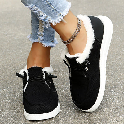 Chaussures noires en daim avec doublure en fourrure blanche, portées avec un jean déchiré et bracelet chaîne, mode décontractée femme.