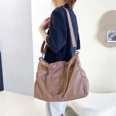 Femme portant un grand sac à main en cuir marron, tenue décontractée, intérieur moderne. Mode féminine, accessoires tendance, style chic.