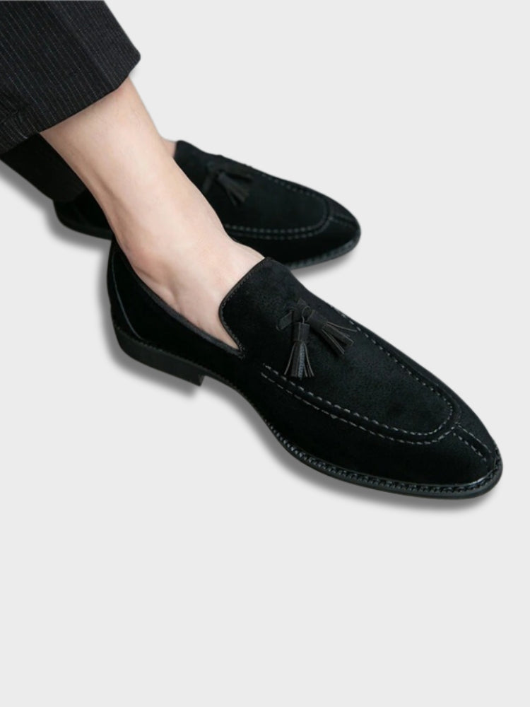 Chaussures mocassins en daim noir avec pampilles, élégantes et modernes, portées avec un pantalon noir. Style chic et tendance pour hommes.