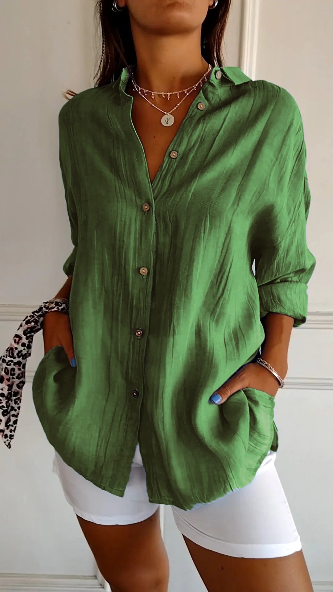 Chemise verte en lin pour femme, manches longues, boutons en bois, portée avec un pantalon blanc. Mode décontractée, élégance estivale.