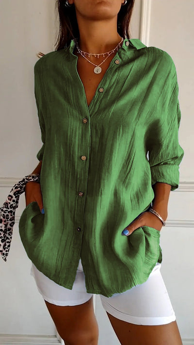 Chemise verte en lin pour femme, manches longues, boutons en bois, portée avec un pantalon blanc. Mode décontractée, élégance estivale.