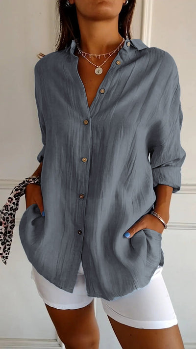 Chemise grise en lin pour femme, manches longues, boutons en bois, poches avant, portée avec un pantalon blanc. Mode décontractée élégante.