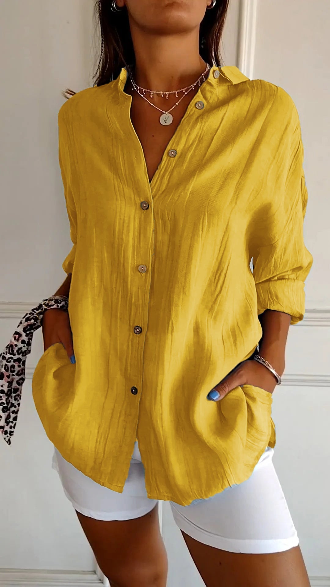 Chemise jaune en lin pour femme, manches longues, boutons en bois, col ouvert, associée à un pantalon blanc. Mode décontractée élégante.