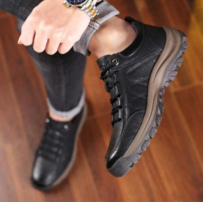 Chaussure de marche noire pour homme, semelle antidérapante, style décontracté, vue de dessus, sur fond de parquet en bois.
