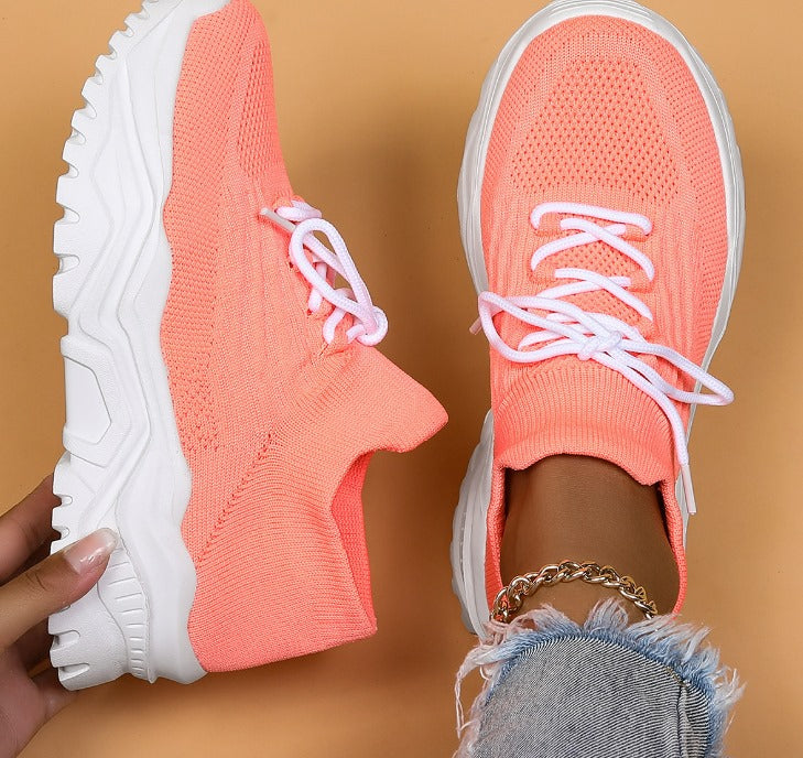 Baskets roses fluo pour femme avec semelle épaisse blanche, lacets blancs, portées avec un jean déchiré. Chaussures tendance et confortables.