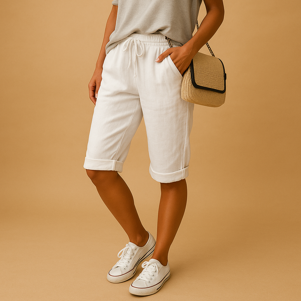 Femme en short blanc en lin, t-shirt gris, baskets blanches, portant un sac en osier. Mode estivale décontractée, style chic et confortable.